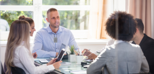 Slechthorend en ondernemer: 4 tips voor ontspannen communicatie met je klant. Afgebeeld staan vijf mensen in overleg aan een ronde tafel.