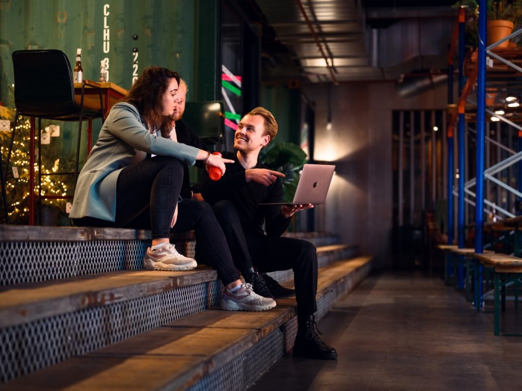 Red Panda Academy levert 400 afstudeerders growth hacking 2022 03 04 Red Panda Academy uitgelicht | Red Panda Academy heeft binnen één jaar 400 afgestudeerde growth hackers afgeleverd. 700 studenten schreven zich in bij deze Growth Hacking Academy van Red Panda Works. | Afgebeeld staan een mannelijke en vrouwelijke student die samen op een lage trap zitten. De mannelijke student houdt een opengeklapte laptop vast, de vrouw wijst naar het scherm.